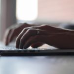Business person typing on laptop for work.